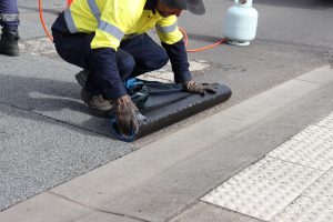 tradie applying crack mat onto a road
